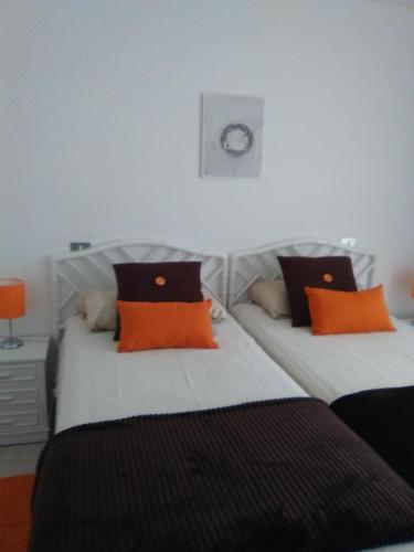 プエルト・デ・ラ・クルスにあるapartamento en parque cardón Puerto cruzのベッドルーム1室(オレンジと黒の枕を使用したベッド2台付)
