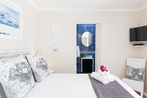 a white bedroom with a bed and a tv at Atlantic Beach Villa in Cape Town