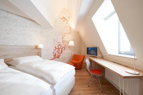 a bedroom with two beds and a desk and a window at Hotel VICTORIA Nürnberg in Nürnberg