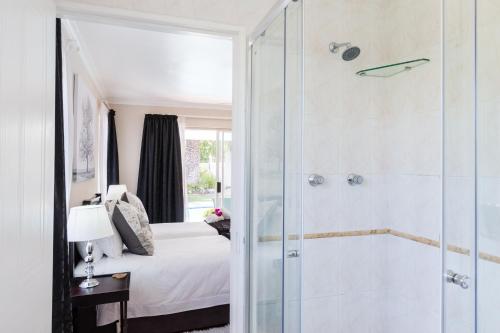a bathroom with a shower and a bedroom with a bed at Atlantic Beach Villa in Cape Town