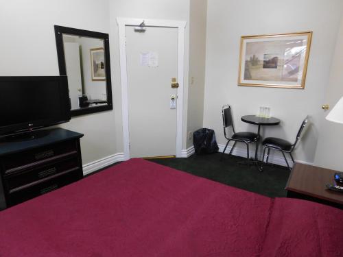 a room with a bed and a tv and a table at Filmores Hotel in Toronto