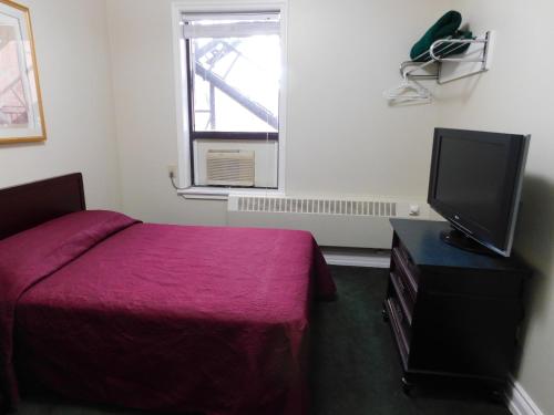 a bedroom with a bed and a flat screen tv at Filmores Hotel in Toronto