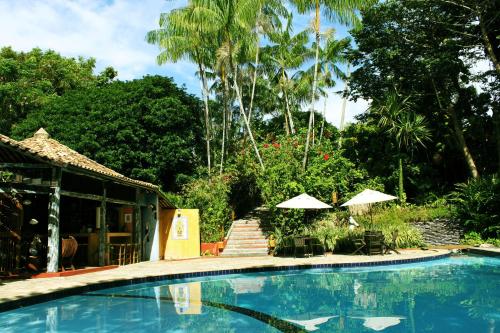 a swimming pool next to a house with umbrellas at Vilangelim Eco-Pousada in Imbassai