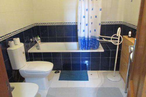 a bathroom with a toilet and a bath tub with a shower curtain at Residencial Marialva Park in Corroios