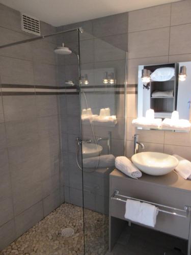 a bathroom with a glass shower and a sink at Contact Hotel de France in Saintes