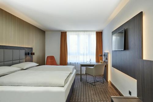 バイロイトにあるH4 ホテル レジデンツシュロス バイロイトのベッドとデスクが備わるホテルルームです。