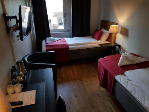 a small room with two beds and a window at City Hotel in Kristinehamn
