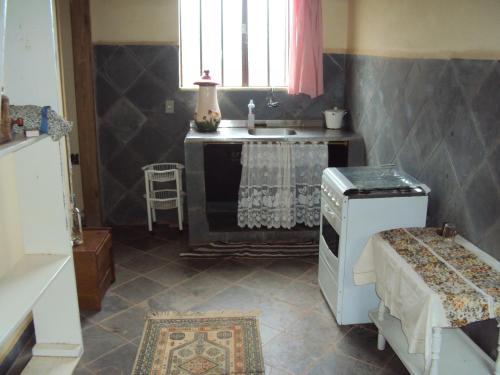 a kitchen with a sink and a counter with a stove at Casas do Adriano in Conceição da Ibitipoca