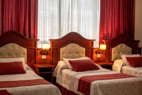 2 camas en una habitación de hotel con cortinas rojas en City Hotel Termal, en Termas de Río Hondo