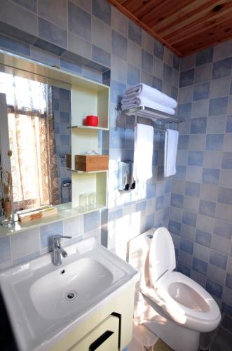 a blue tiled bathroom with a sink and a toilet at Peace Inn The Leshan Giant Buddha Branch in Leshan