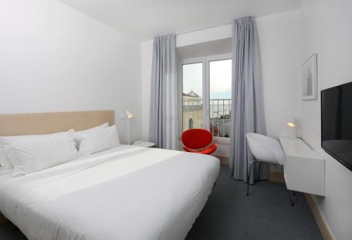 een hotelkamer met een groot bed en een rode stoel bij Hotel Convento do Salvador in Lissabon