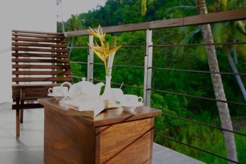 a table with cups and a vase with flowers on it at Nature Trails Boutique Hotel in Unawatuna