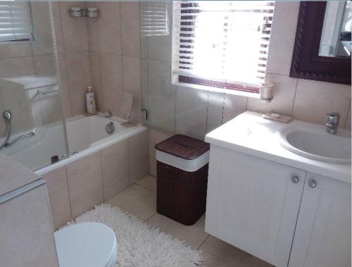 a bathroom with a sink and a tub and a toilet at Whale Rock Gardens in Plettenberg Bay