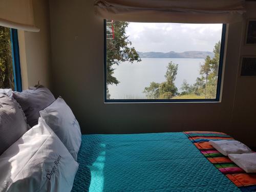 a bedroom with a window with a view of a lake at Cabañas Yukatan Lago de Tota in Tota