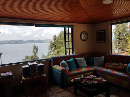 a living room with a couch and a large window at Cabañas Yukatan Lago de Tota in Tota