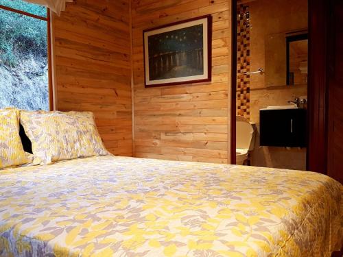 a bedroom with a bed in a room with wooden walls at Cabañas Yukatan Lago de Tota in Tota