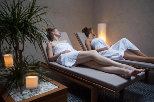 two women in towels sitting in beds in a room at Prezident Luxury Spa & Wellness Hotel in Karlovy Vary