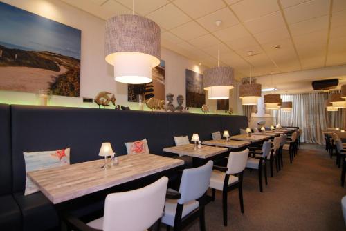 une rangée de tables et de chaises dans un restaurant dans l'établissement Hotel de Burg, à Domburg