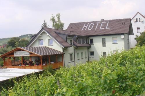 a hotel building with people sitting on a deck in a vineyard at Landhotel Weingut Schulze in Freyburg