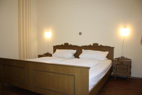 a bedroom with a large bed with white sheets and two lamps at Gasthof und Pension Zur Frischen Quelle in Heigenbrücken