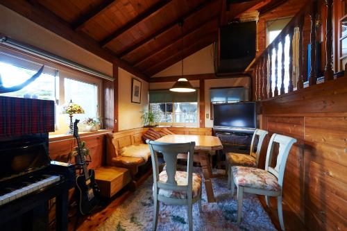 a dining room with a table and chairs and a piano at Lake village donaludo Pension in Kitashiobara