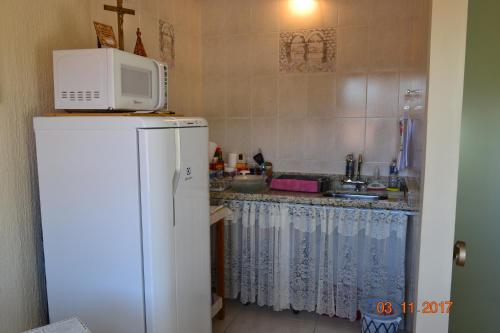 a kitchen with a microwave on top of a refrigerator at Hospedaria Servos de Maria in Aparecida