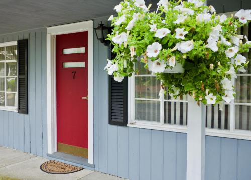 a blue house with a red door and areath of white flowers at The Grayhaven Motel in Ithaca
