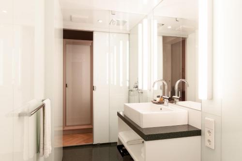 a white bathroom with a sink and a mirror at OSTKÜSTE - Villa Staudt Design Apartments in Heringsdorf