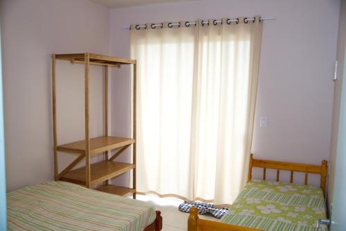 1 dormitorio con 1 cama y una ventana con cortinas en Residencial Oceano Azul en Itapoa