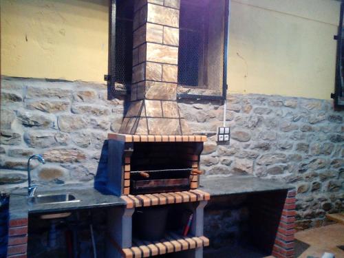 a kitchen with a stone stove with a sink at Toño el Alguacil in Selaya