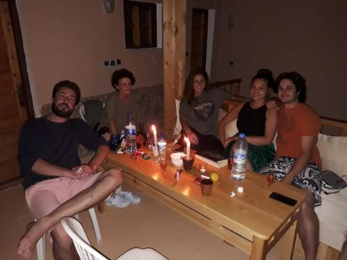 un grupo de personas sentadas alrededor de una mesa con velas en Playa Surf House, en Taghazout