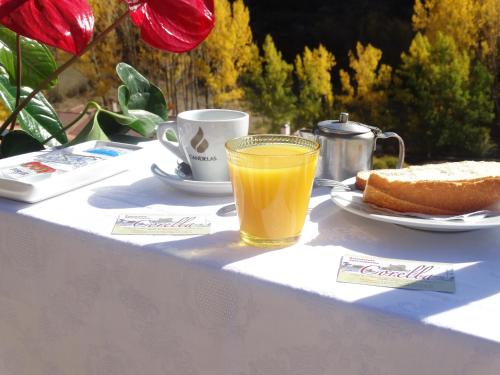 ein Tisch mit einer Tasse Orangensaft und einem Stück Brot in der Unterkunft Apartamentos El Pajar Alcala de la Selva in Alcalá de la Selva