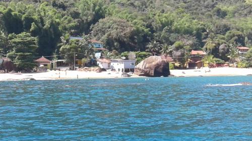 a large rock in the water next to a beach at Nena's Suítes in Praia de Araçatiba