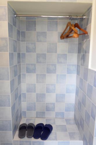 a shower with blue and white tiles with pairs of shoes at Peace Inn The Leshan Giant Buddha Branch in Leshan