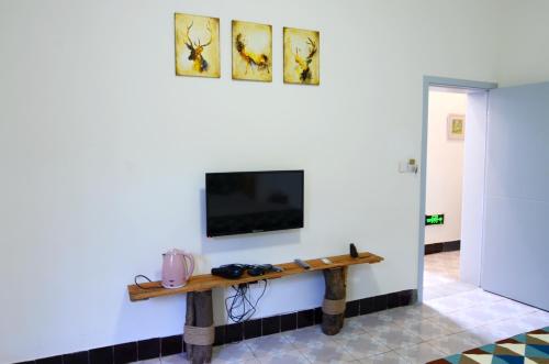 a living room with a tv on a white wall at Peace Inn The Leshan Giant Buddha Branch in Leshan