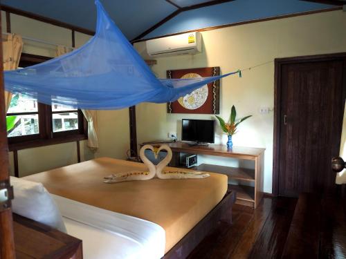 a bedroom with a bed with a blue canopy at LITTLE EDEN Bungalows in Ko Chang