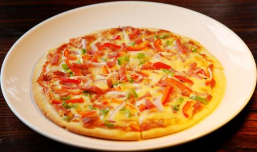 a pizza on a white plate on a table at Yangshuo Coco Garden Hotel in Yangshuo