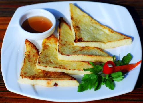 a white plate with grilled cheese sandwiches and a cup of tea at Yangshuo Coco Garden Hotel in Yangshuo
