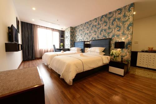 ein großes Schlafzimmer mit 2 Betten und einem Wandbild in der Unterkunft Hanoi Emerald Waters Hotel & Spa in Hanoi