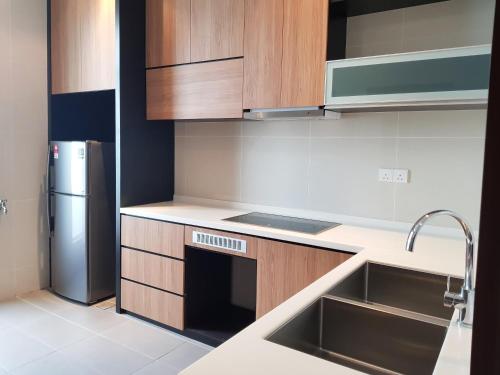 a kitchen with wooden cabinets and a stainless steel refrigerator at KSL Hotel & Resort in Johor Bahru