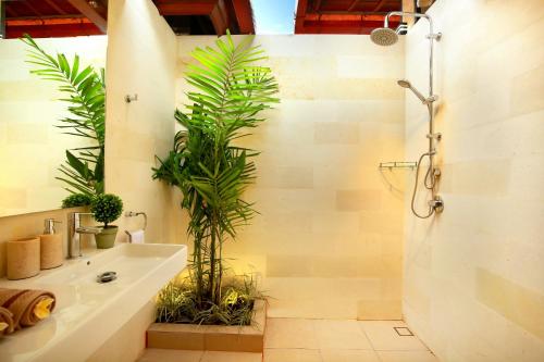 a bathroom with a sink and a shower with plants at De Liza Villa Seminyak Beachside in Seminyak