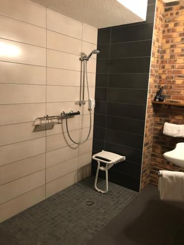 uma casa de banho com um chuveiro e um banco. em Hotel Restaurant Aux Trois Roses em La Petite-Pierre