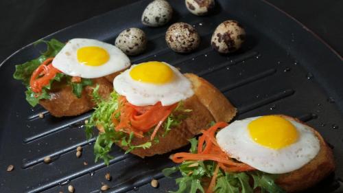 a sandwich with eggs on a black plate with chicks at Bali Umah Tinjung in Tulamben