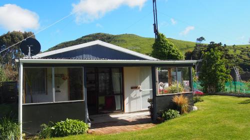 a small house with a green hill in the background at Kepplestone by the Sea - The Catlins in New Haven