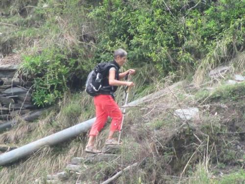 a man with a backpack walking up a hill at Trimurti Pine Valley Resort in Shimla