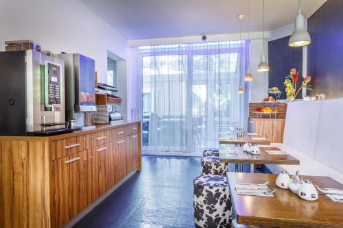 
a kitchen with a refrigerator, microwave, coffee maker and a table at Hotel Victorie in Amsterdam
