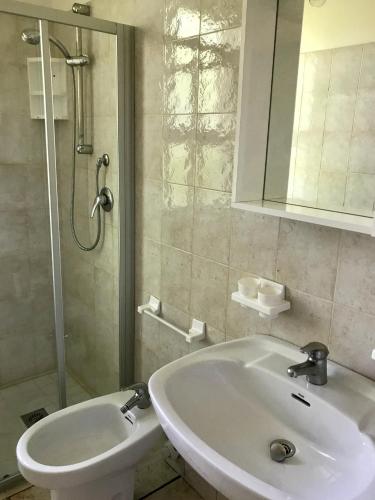 a white bathroom with a sink and a shower at Ville Verdi - private garden in Bibione