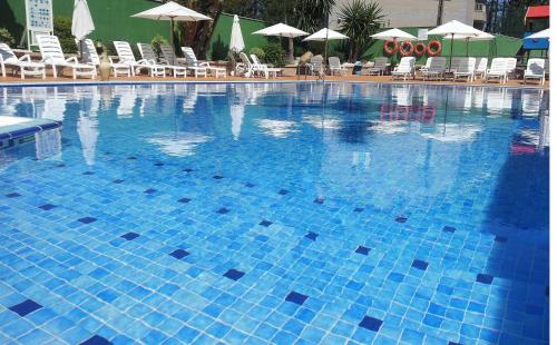 una gran piscina azul con sillas y sombrillas en Apartamentos Marsil, en Montalvo