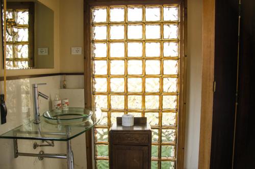 baño con lavabo de cristal y ventana en B&B La Finestra sul Fiume, en Vaprio dʼAdda