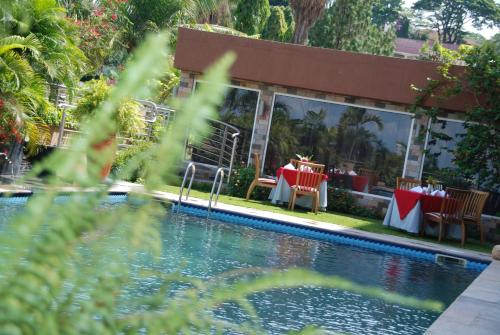a restaurant with tables and chairs next to a swimming pool at Kiriri Garden Hotel in Bujumbura